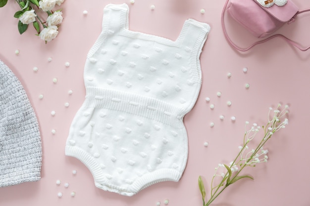 Bovenaanzicht van baby meisje accessoires achtergrond, baby body jumpsuit, handtas, bloemen en speelgoed over roze achtergrond met kopie ruimte; uitzicht van bovenaf, plat gelegd