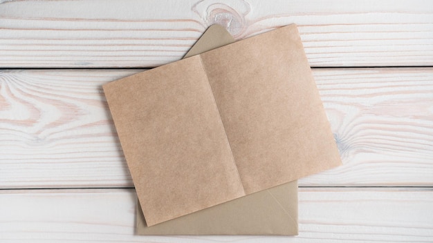 Bovenaanzicht van blanco bruin gerecycleerd ambachtelijk papier op open ambachtelijke envelop op grijze houten tafel Correspondentierecycling