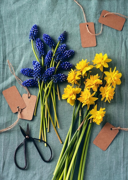 Bovenaanzicht van blauwe druivenhyacint en gele dubbele narcisbloemen op een turkoois linnen tafelkleed