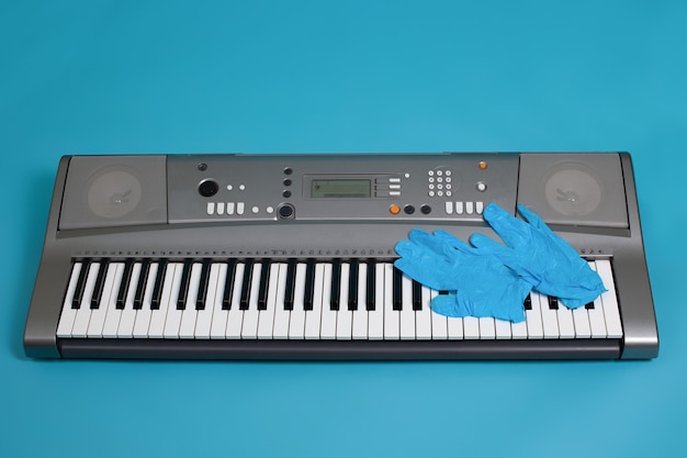 Bovenaanzicht van blauwe medische handschoenen op de toetsen van een grijze elektronische synthesizer