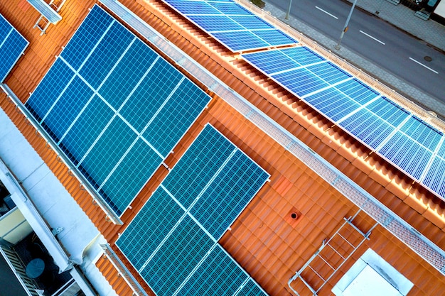 Bovenaanzicht van blauwe zonnepanelen op hoog flatgebouwdak.