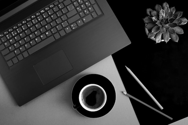 Bovenaanzicht van bureau met laptop koffiekopje cactus en potloden op de zwarte en grijze achtergrond Flat lay