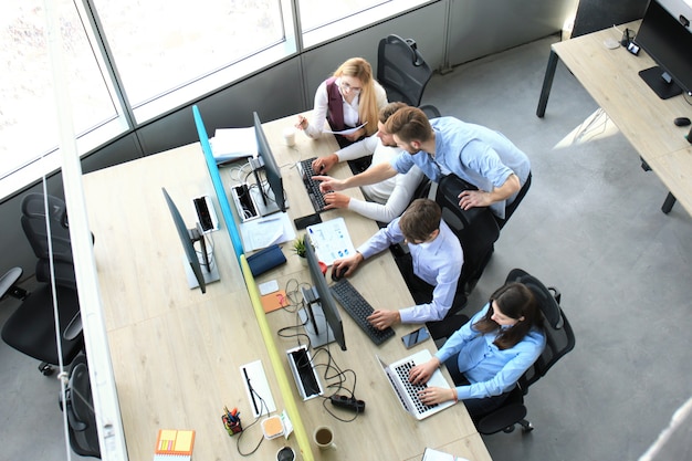 Bovenaanzicht van business team brainstormen terwijl u samen aan de kantoortafel zit.