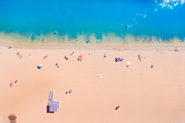 Bovenaanzicht van de azuurblauwe Resortzee met prachtig water en mensen die op de kust rusten. Geel warm zand en azuurblauw schoon water.