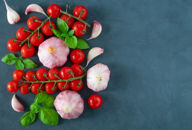 Bovenaanzicht van de close-up van cherrytomaatjes, knoflook en verse basilicum bladeren als ingrediënten voor het koken.