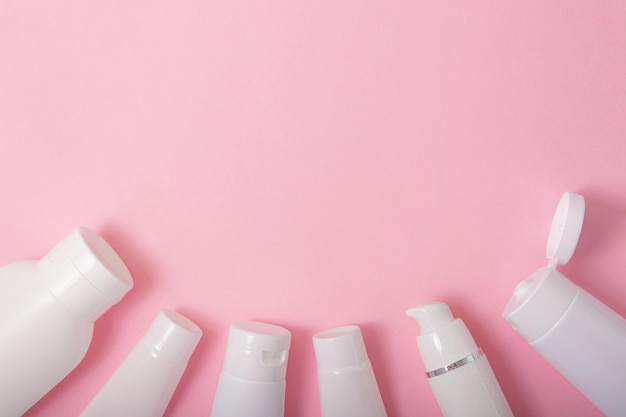 Bovenaanzicht van de cosmetica-containers op roze achtergrond met negatieve ruimte. Goed voor nieuwjaarsaanbieding en tekstoverlay.