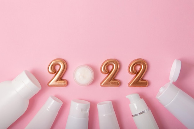 Bovenaanzicht van de cosmeticacontainers op roze achtergrondRose gouden nummers 2022 hierboven