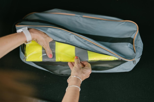 Bovenaanzicht van de handen van een vrouw die een reflecterend vest uit een tas haalt