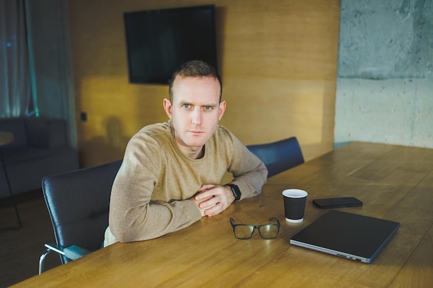 Bovenaanzicht van de man in casual kleding met koffie zittend op de werkplek met netbook tijdens het werken tijdens de werkdag Een succesvolle zakenman werkt op een laptopcomputer