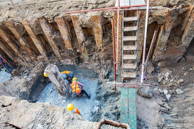 Bovenaanzicht van de mannelijke arbeider was een betonmachine aan het pleisteren met een in een gat aan het graven met een graafmachine in besloten ruimtes. Er zat aarde omheen