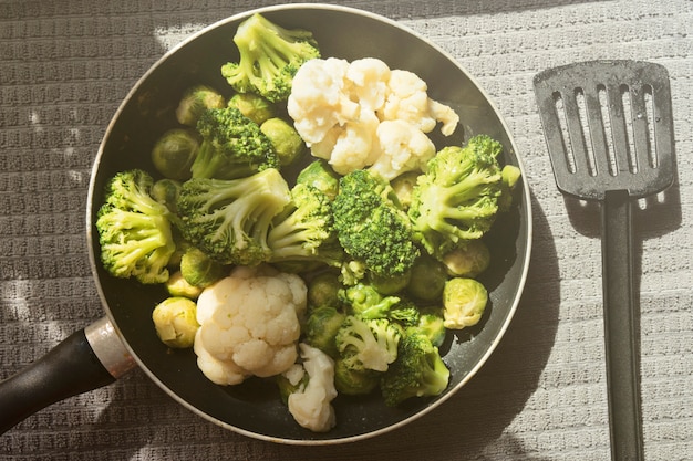 Bovenaanzicht van de pan met verse, ontdooide groenten: bloemkool, broccoli, spruitjes