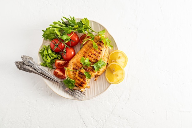 Bovenaanzicht van de serveerschaal met gegrilde kipfilet en vers gesneden groenten witte achtergrond een kopie van het ruimtemenu