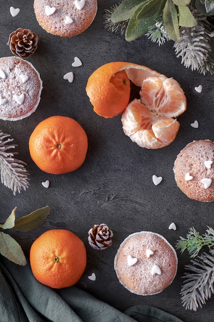 Bovenaanzicht van de tafel met satsuma&#39;s, suikerstroop muffins en kerststerren cookies op donker