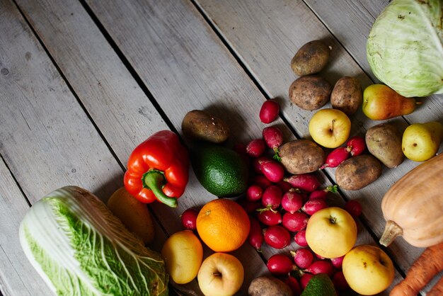 Foto bovenaanzicht van de vegetarische set, bestaande uit groenten en fruit liggend op de houten tafel