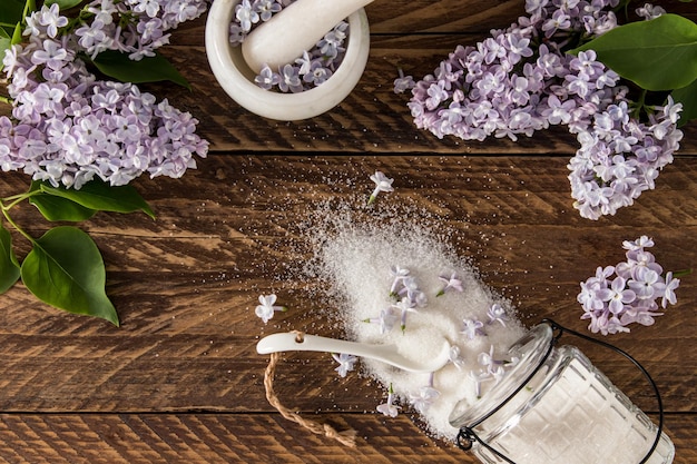 Bovenaanzicht van de verspreide suiker van lila bloemen op de houten tafel takken seringen het concept van het gebruik van eetbare planten bij het koken