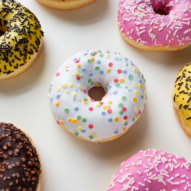 Bovenaanzicht van diverse donuts met frosted chocolade, roze geglazuurd en hagelslag