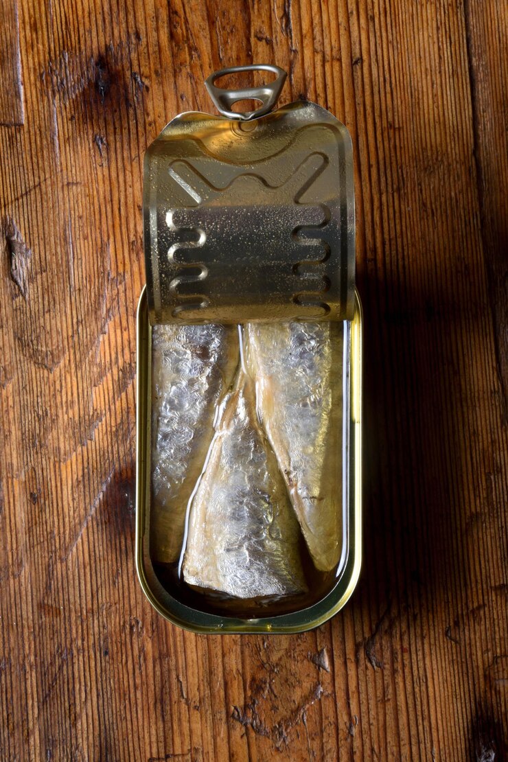 Foto bovenaanzicht van een blikje sardines op houten achtergrond