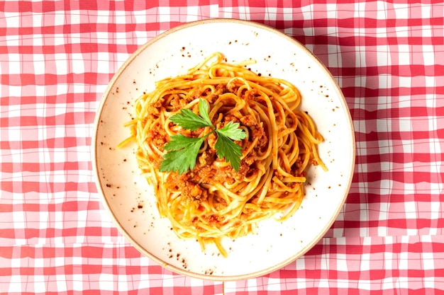 Bovenaanzicht van een bord spaghetti bolognese op een rood en wit geruit tafelkleed