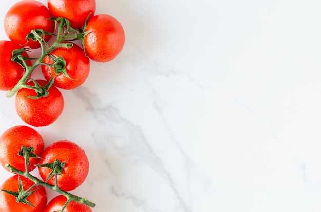 Bovenaanzicht van een bos verse tomaten op een witte marmeren achtergrond