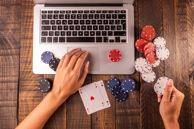 Bovenaanzicht van een computer met pokerfiches en kaarten om in te zetten of te spelen.