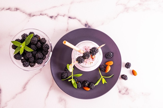 Bovenaanzicht van een fles vers gemaakte smoothies of een cocktail met noten en bramen marmeren witte achtergrond heerlijke dessertsnack