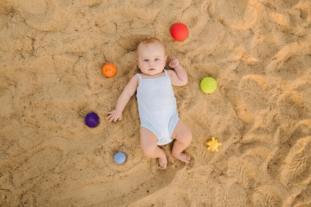 Bovenaanzicht van een gelukkige kleine jongen liggend op een zandstrand