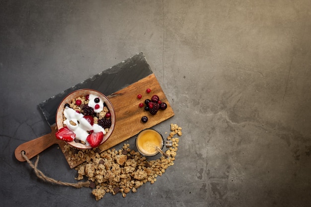 Bovenaanzicht van een gezond ontbijt met muesli, yoghurt en seizoensbessen op een concrete achtergrond