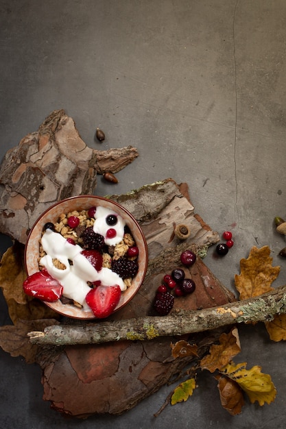 Bovenaanzicht van een gezond ontbijt met muesli, yoghurt en seizoensbessen op een concrete achtergrond