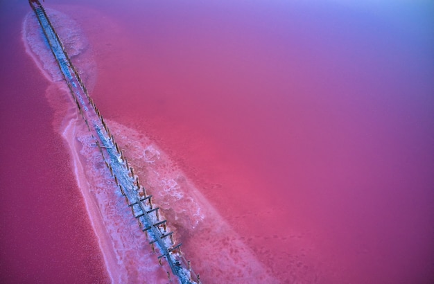 Bovenaanzicht van een glanzend zout roze meer en een pad erlangs