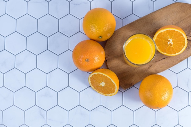 Bovenaanzicht van een glas geperst sinaasappelsap op een tafel met sinaasappels eromheen