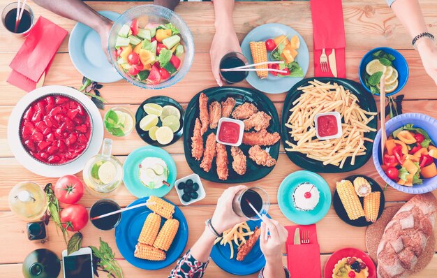 Foto bovenaanzicht van een groep mensen die samen dineren terwijl ze aan een houten tafel zitten voedsel op tafel mensen eten fastfood