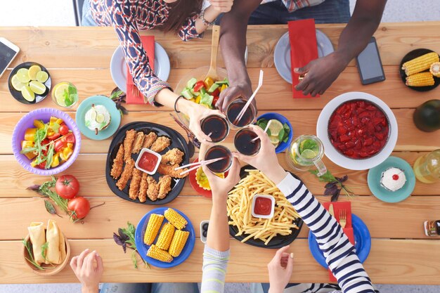 Foto bovenaanzicht van een groep mensen die samen dineren terwijl ze aan een houten tafel zitten voedsel op tafel mensen eten fastfood