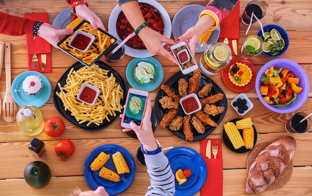 Foto bovenaanzicht van een groep mensen die samen dineren terwijl ze aan een houten tafel zitten