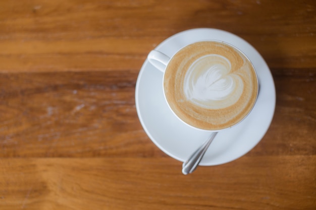 Bovenaanzicht van een hart gevormd in een kopje latte, cappuccino koffie. Cafe kunst met melk