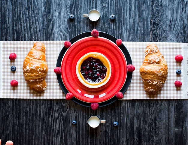 Bovenaanzicht van een houten tafel vol cakes, fruit, koffie, koekjes, kruiden en meer