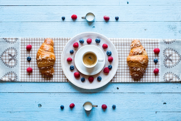 Bovenaanzicht van een houten tafel vol cakes, fruit, koffie, koekjes, kruiden en meer