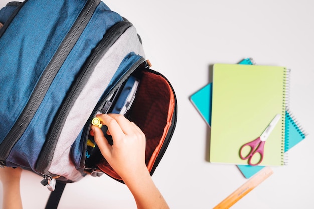 Bovenaanzicht van een kinderhand die een stift uit zijn schooltas haalt Notitieboekjes en linialen