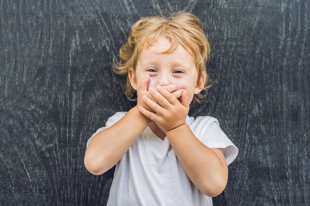 Bovenaanzicht van een kleine blonde jongen jongen met ruimte voor tekst en symbolen op de oude houten achtergrond. concept voor verwarring, brainstormen en keuze. kopieer ruimte