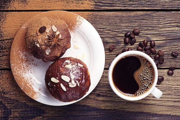 Bovenaanzicht van een kopje koffie en cupcake met chocolade en noten op houten tafel