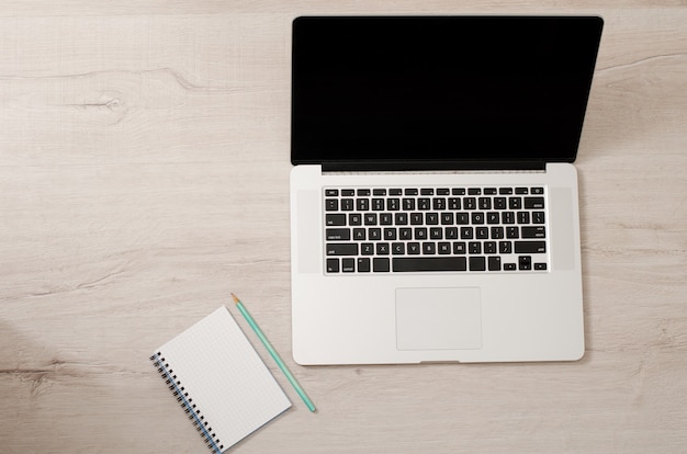 Foto bovenaanzicht van een laptop en een notebook met een potlood op een lichte houten achtergrond, ruimte voor tekst