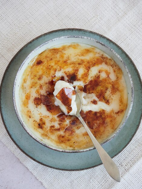 Bovenaanzicht van een lepel romige rijstpudding in de traditionele Asturische stijl geserveerd in een kom met een heerlijke zoete gekarameliseerde suikerkorst