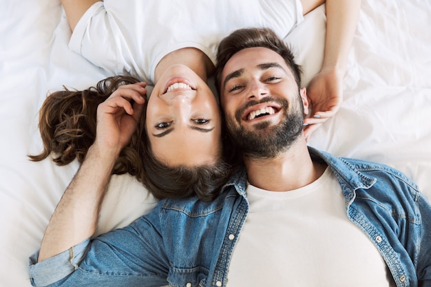 Bovenaanzicht van een mooi jong verliefd stel thuis, liggend op bed