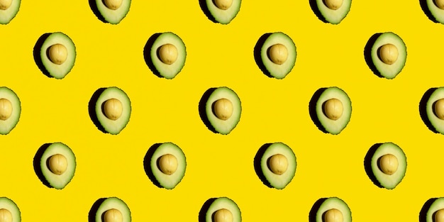 Bovenaanzicht van een naadloos patroon van groene avocado's met een steen op een gele achtergrond Gezond zomervoedsel