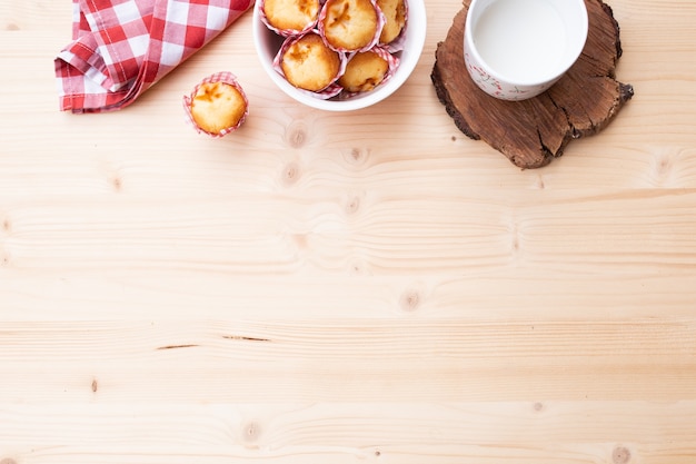 Bovenaanzicht van een ontbijt met muffins en een kopje melk, vergezeld van een rode doek met kopie ruimte