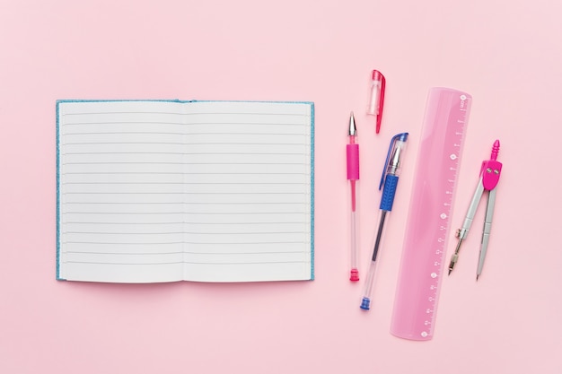 Bovenaanzicht van een open notebook met lege pagina en roze pen. Terug naar school-concept.