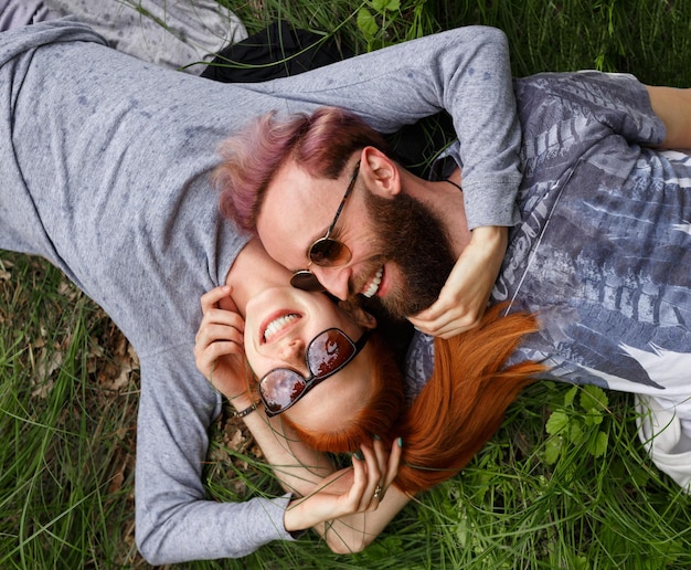 Bovenaanzicht van een paar, zittend op een groen gras, zittend met gedraaide hoofden met gesloten ogen. Paar relatie.