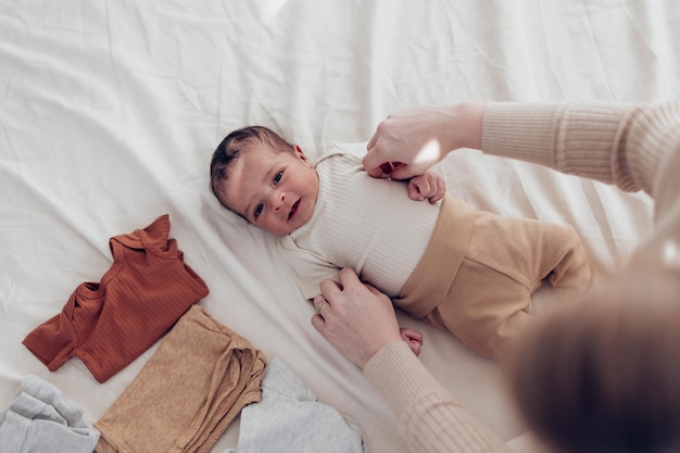 Foto bovenaanzicht van een pasgeboren baby op het bed, moeder draagt kleren voor haar kleine kind