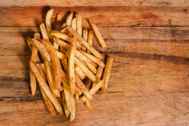 Bovenaanzicht van een persoonlijke portie frites op een houten tafel.