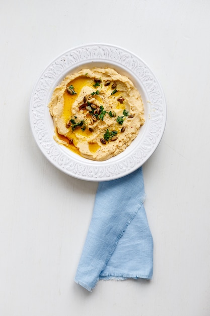 Bovenaanzicht van een plaat van gezonde zelfgemaakte romige hummus op grijs