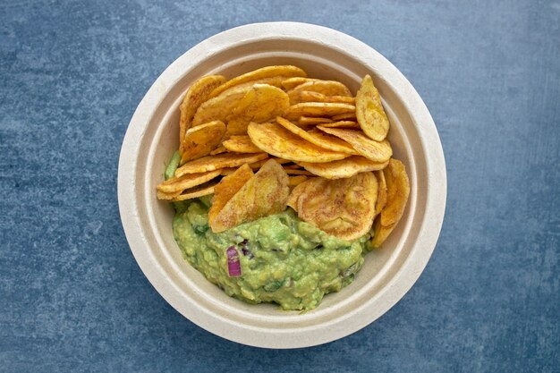 Bovenaanzicht van een portie gebakken weegbree-chips met guacamole.